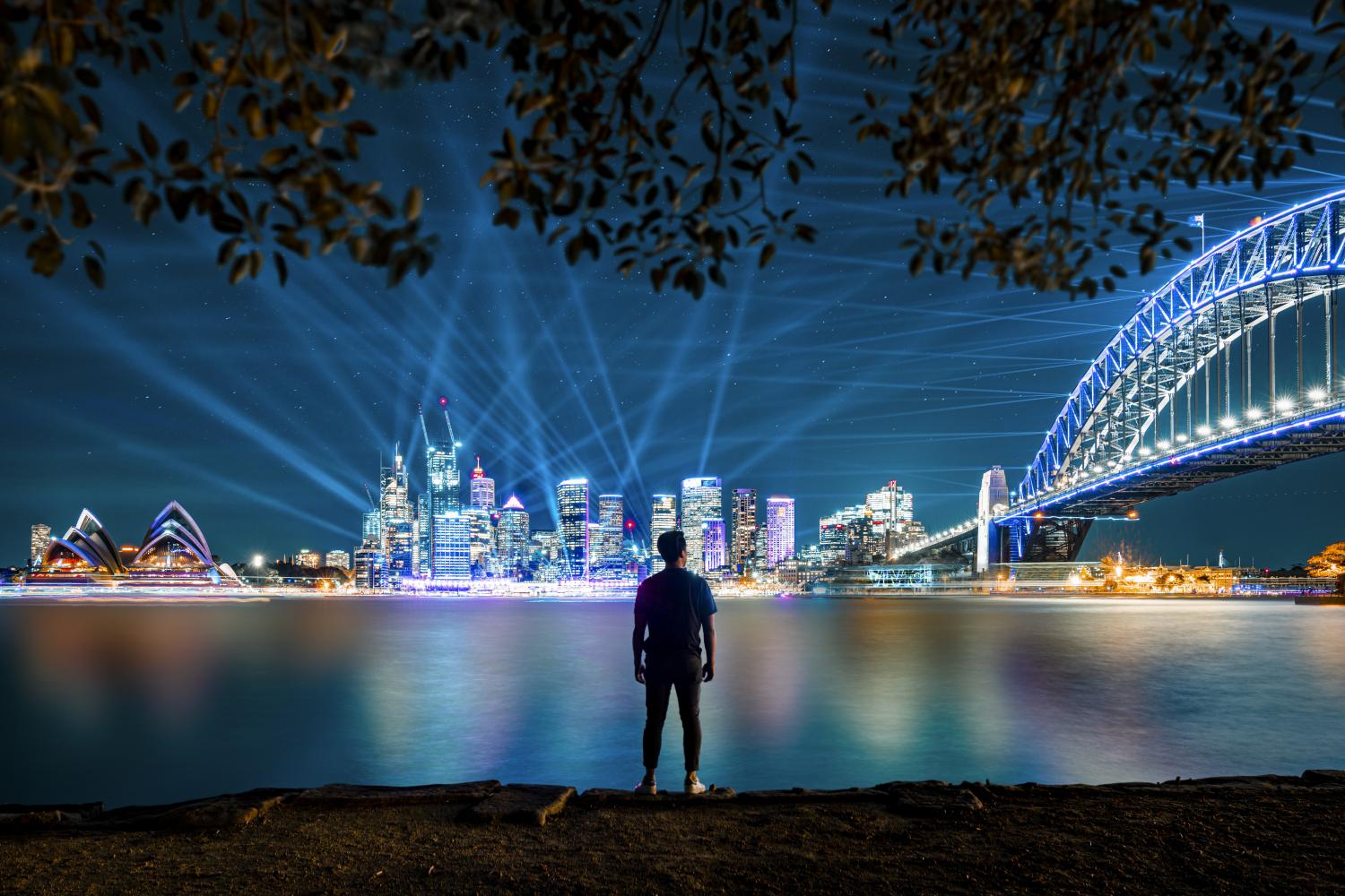 Man watching the City Sparkle light projection and installation on the Sydney Harbour Bridge from Kirribilli during Vivid Sydney