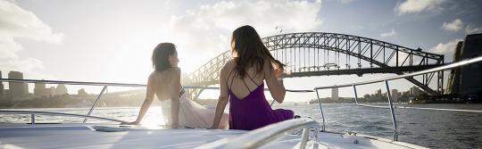 坐在航行於悉尼海港遊艇前部的兩位女士